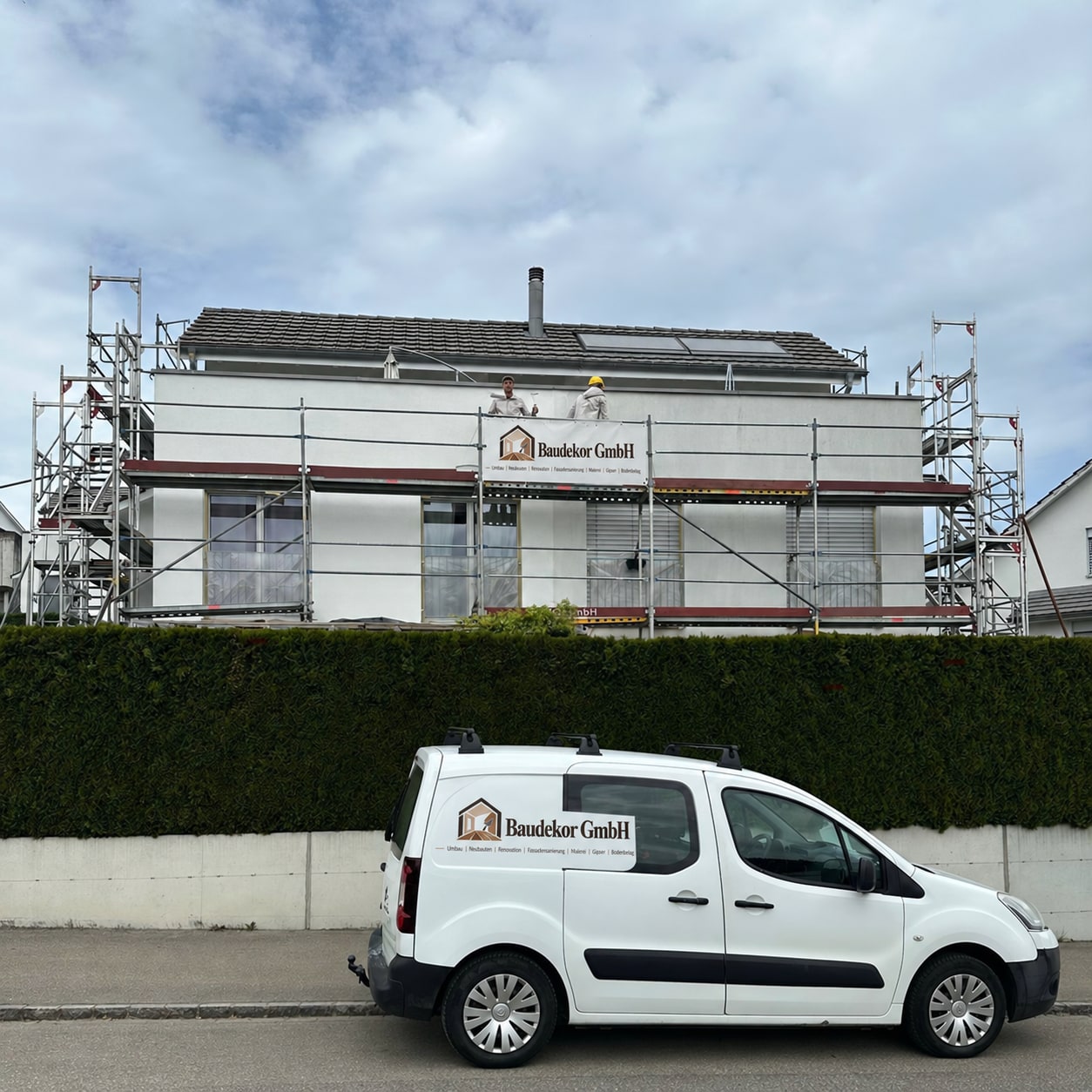 Fassade in Lufingen mit Baugerüst, Baudekor-Banner und Firmenfahrzeug